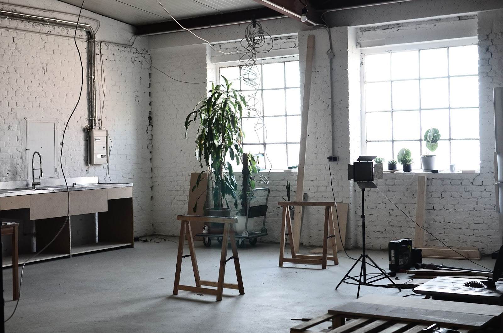 Industrial loft space with large windows, indoor plants, and studio equipment